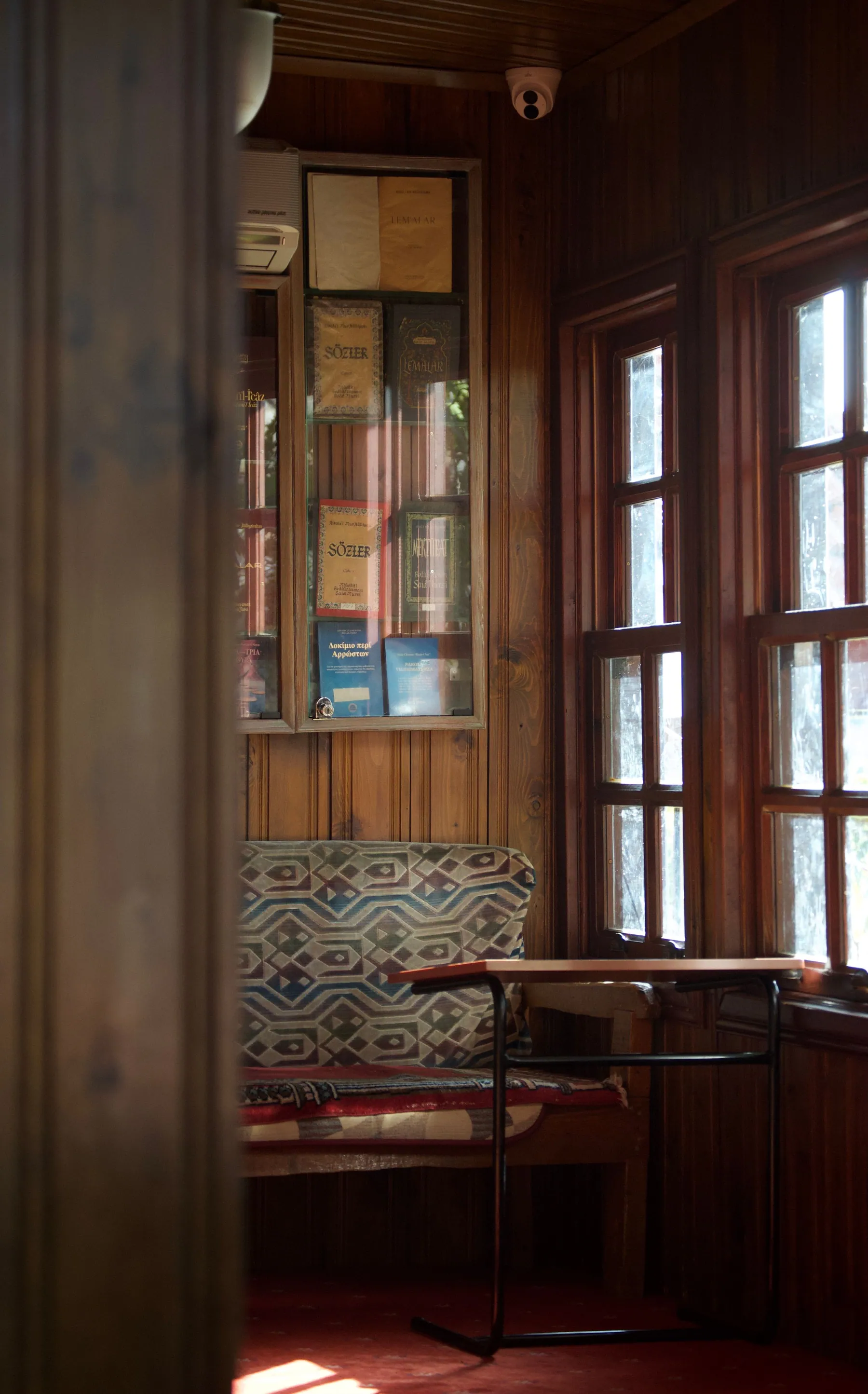 An empty seat beside a warm wooden window in soft daylight
