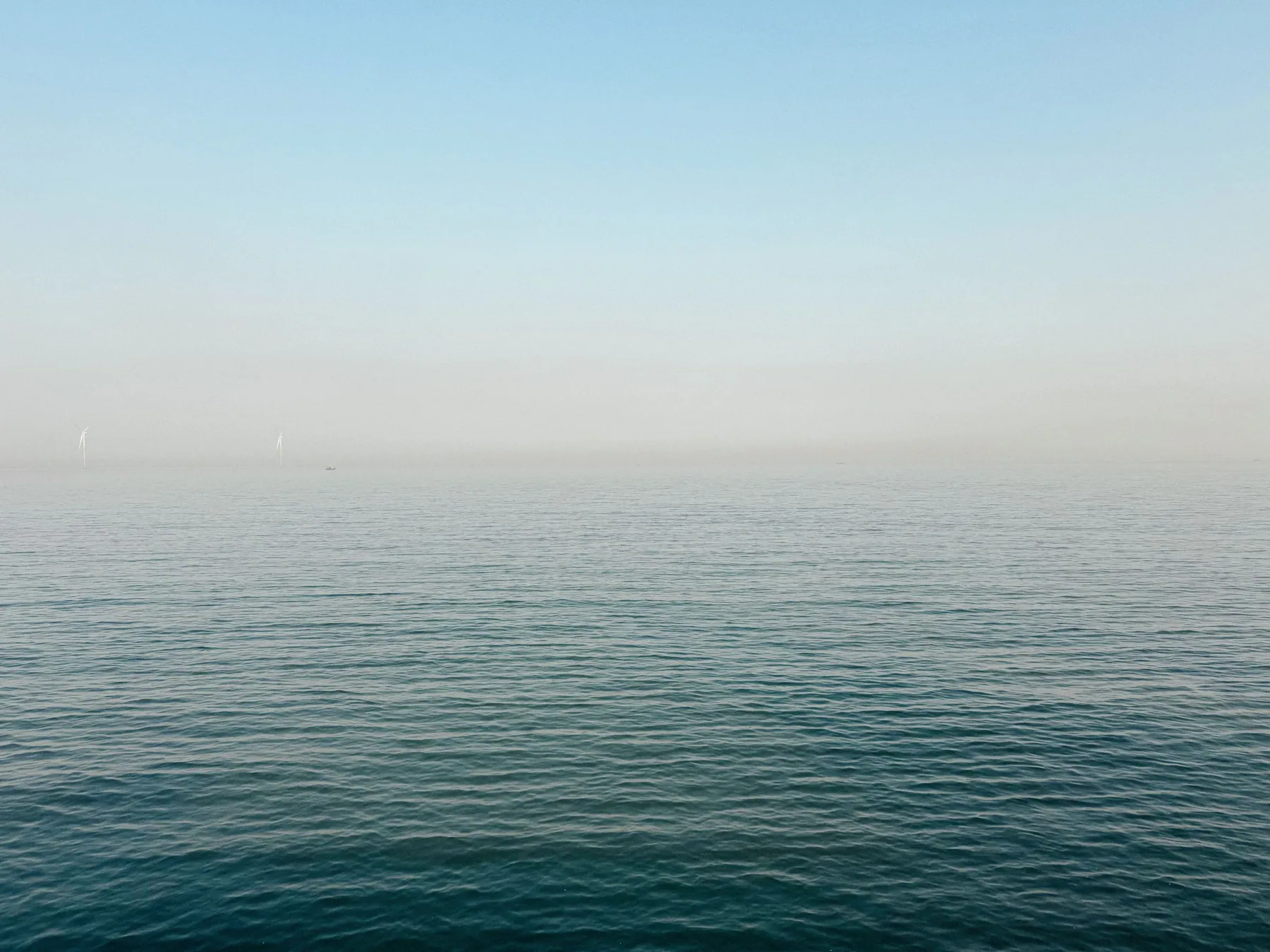 A calm sea meeting a soft, misty horizon